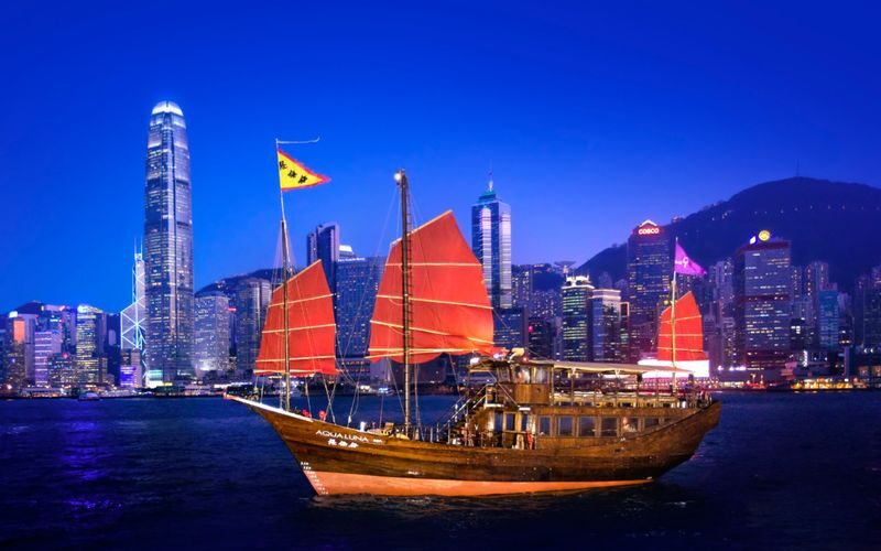 Aqua Luna Victoria Harbour Cruise Experience - A traditional red sail against Hong Kong’s towers